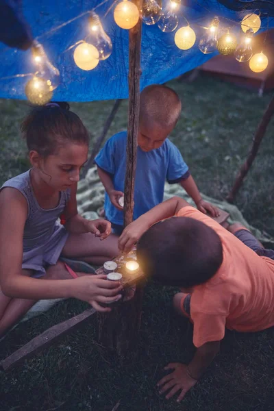Crianças fazendo uma pequena tenda com velas e lampiões no backya — Fotografia de Stock