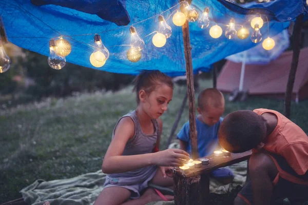 Crianças fazendo uma pequena tenda com velas e lampiões no backya — Fotografia de Stock