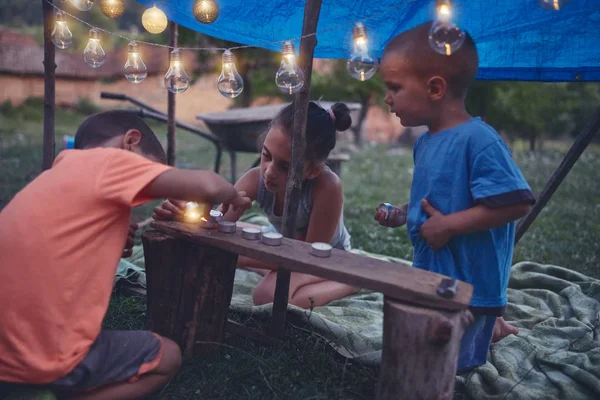 Kinder basteln ein kleines Zelt mit Kerzen und Lampions im Hintergrund — Stockfoto