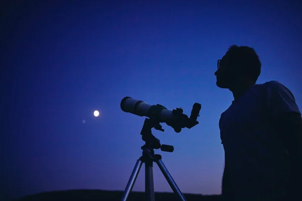 Astronomen med ett teleskop som tittar på stjärnorna och månen. Min också. — Stockfoto