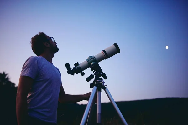 Astronomen med ett teleskop som tittar på stjärnorna och månen. Min också. — Stockfoto