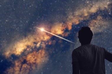 Gece gökyüzünü ve Samanyolu 'nu kayan bir yıldızla izleyen bir adam.