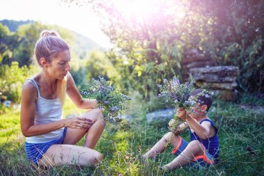 Anne ve oğul doğada çiçek / bitki topluyor..