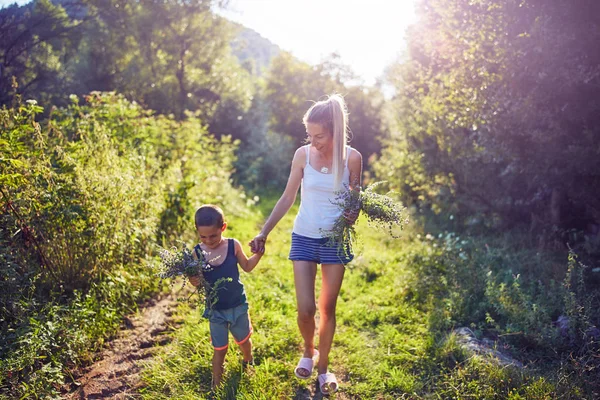 Mutter und Sohn pflücken Blumen / Kräuter in der Natur. — Stockfoto