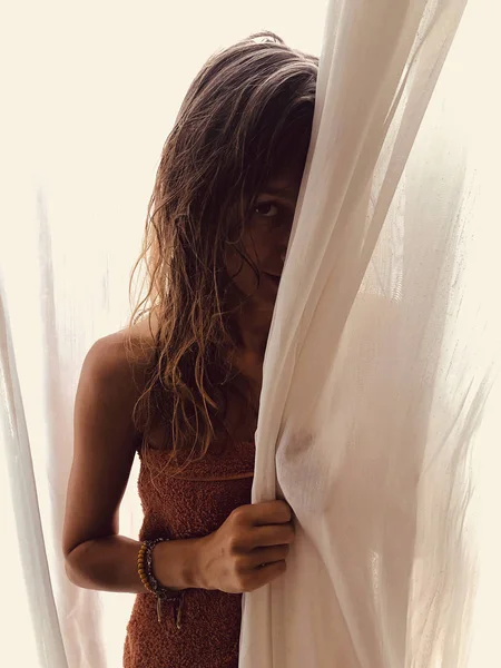 Mujer escondida detrás de la cortina de la ventana . —  Fotos de Stock