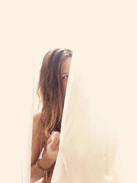 Žena skrývající se za záclonou uvnitř. — Stock fotografie