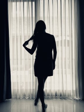 Pencerenin önünde ve perdede havlusu olan kadın..