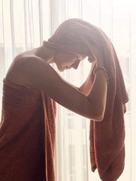窗户和窗帘前拿毛巾的女人. — 图库照片
