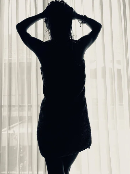 Mujer con toalla delante de una ventana y cortina . — Foto de Stock