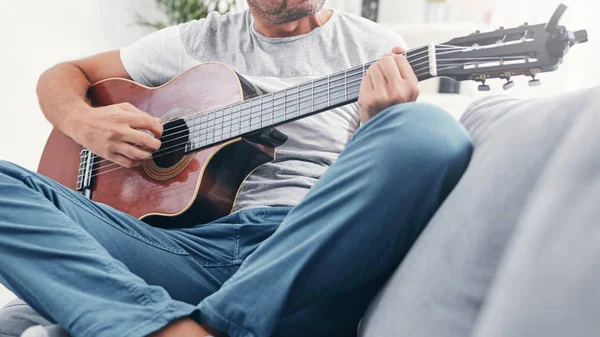 거실에서 어쿠스틱 기타를 연주하는 남자. — 스톡 사진