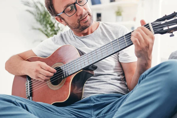 Чоловік грає на акустичній гітарі у вітальні . — стокове фото