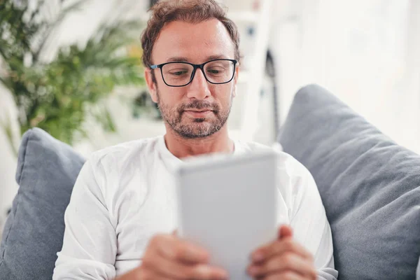 Hombre usando tableta y sufring en el Internet en su sala de estar . — Foto de Stock