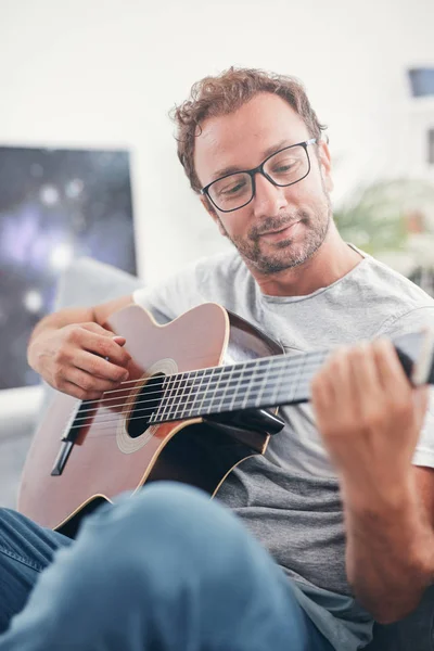 거실에서 어쿠스틱 기타를 연주하는 남자. — 스톡 사진