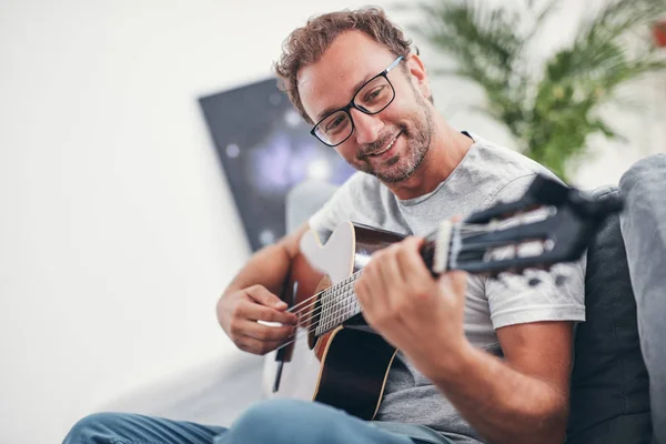 Uomo che suona la chitarra acustica in salotto . — Foto Stock