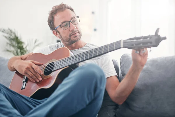 Чоловік грає на акустичній гітарі у вітальні . — стокове фото