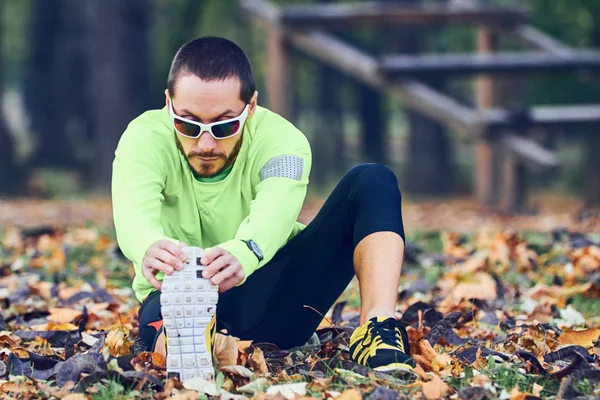 Hombre estirándose después del ejercicio en el parque . — Foto de Stock