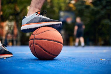 Adam şehir sahasında basketbol topunu durduruyor..