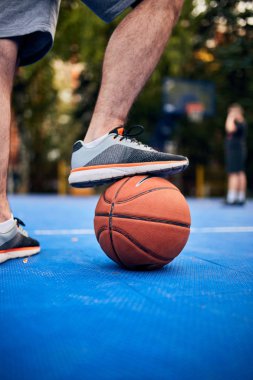 Adam şehir sahasında basketbol topunu durduruyor..