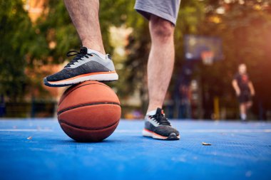 Adam şehir sahasında basketbol topunu durduruyor..