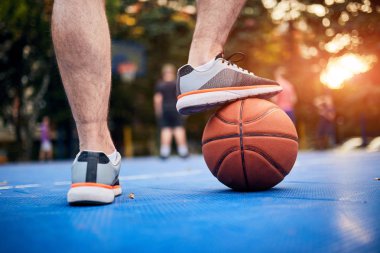 Adam şehir sahasında basketbol topunu durduruyor..