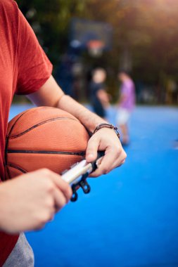 Basketbol topunu şehir merkezinde elle pompalayan bir adam.