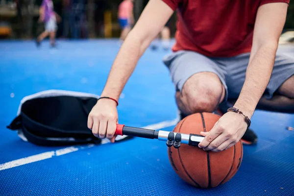 Homem bola de basquete inflável com uma bomba de mão no cour urbano — Fotografia de Stock