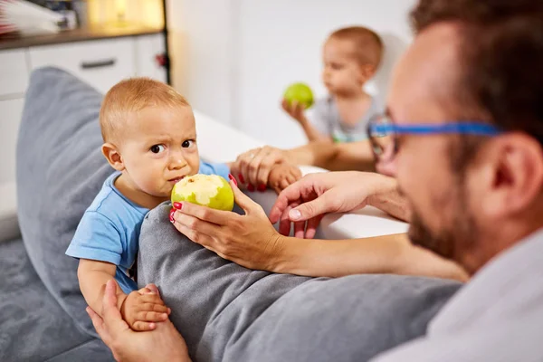 Parents feeding their baby with healthy green apple.