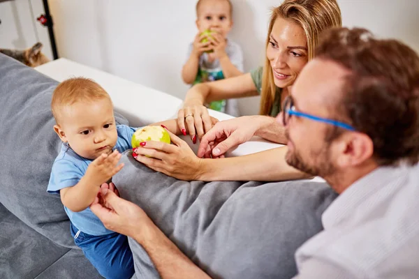 Parents feeding their baby with healthy green apple.