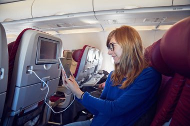 Modern uçak koltuğunda cep telefonu kullanan bir kadın..