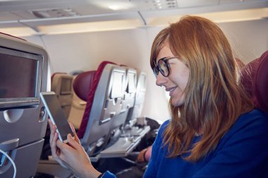 Modern uçak koltuğunda cep telefonu kullanan bir kadın..
