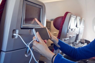 Modern uçak koltuğunda cep telefonu kullanan bir kadın..