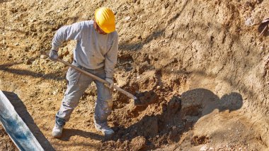 Ağır bir sitede inşaat işçisi sıkı çalışma yapıyor.