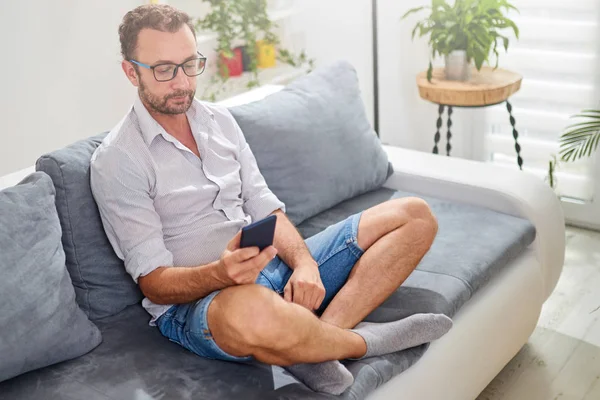 Hombre usando smartphone en la sala de estar . — Foto de Stock