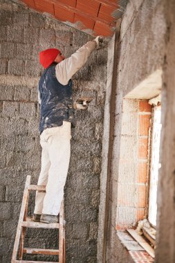 Gerçek inşaat işçisi yeni evin içinde bir duvar yapma.