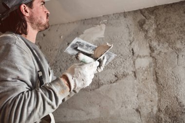 İnşaat işçisi evin içine alçıtaşı duvarları yapıştırıyor..