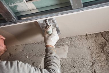 İnşaat işçisi evin içine alçıtaşı duvarları yapıştırıyor..