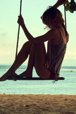Genç bir kadın kumlu bir plajda sallanıyor..