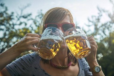 Sevimli kız iki bardak bira açık havada oyun.