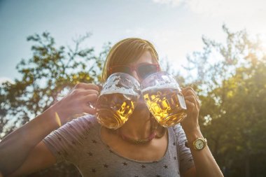 Sevimli kız iki bardak bira açık havada oyun.