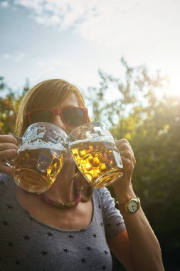 Sevimli kız iki bardak bira açık havada oyun.