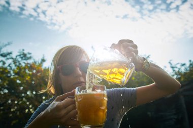 Sevimli kız iki bardak bira açık havada oyun.