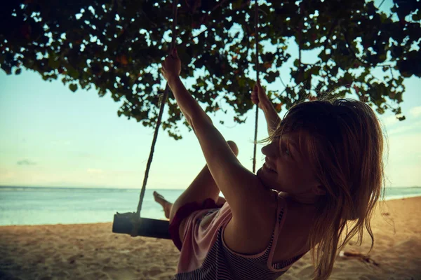 Ung kvinna svänger på en sandig tropisk strand. — Stockfoto