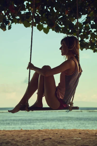 Mujer joven balanceándose en una playa tropical de arena . — Foto de Stock