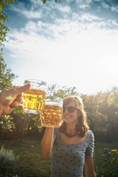 Pareja sosteniendo vasos de cerveza en el aire desde el punto de vista personal — Foto de Stock