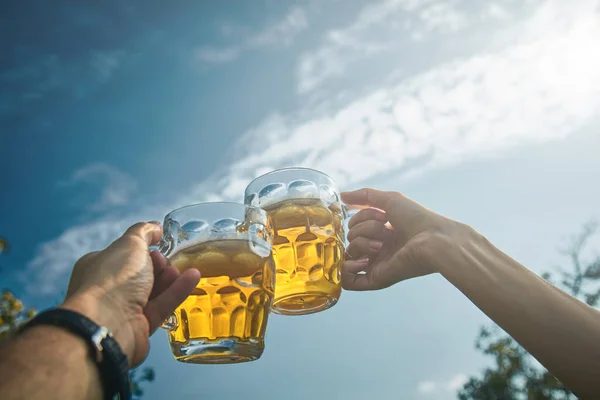 Pareja sosteniendo vasos de cerveza en el aire desde el punto de vista personal — Foto de Stock