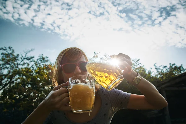 Menina bonito jogar com dois copos de cerveja ao ar livre . — Fotografia de Stock