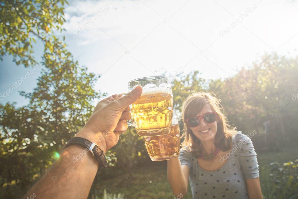 Pair holding beer glasses in the air from personal point of view
