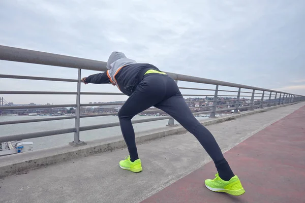 Un sportif s'entraîne / fait du jogging sur un pont urbain d'une grande ville . — Photo