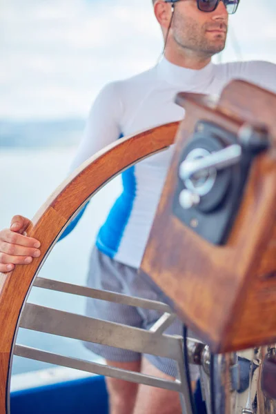 Моряк использует колесо для управления рулем на парусной лодке . — стоковое фото