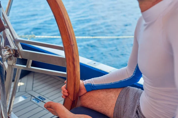 Marinaio utilizzando la ruota per sterzare timone su una barca a vela . — Foto Stock